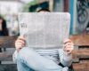 man sitting on bench reading newspaper