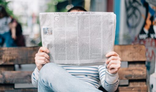 man sitting on bench reading newspaper